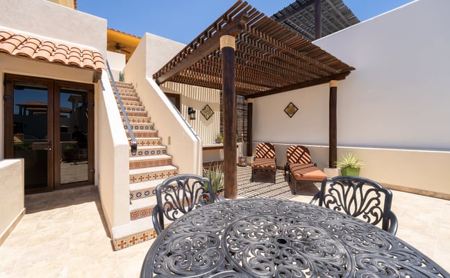 Outdoor patio with tiled staircase, pergola, and iron dining table at a Loreto Bay home