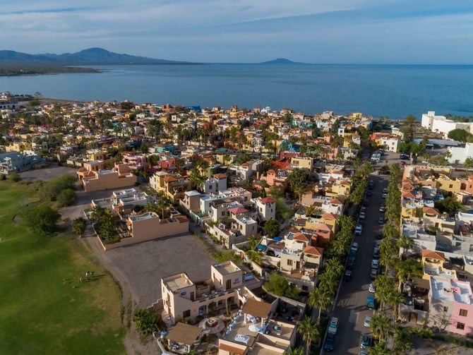 Aerial view of Loreto Bay town with colourful rooftops, palm trees, and the Sea of Cortez