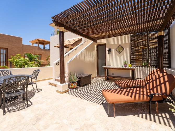 Rooftop terrace with sun loungers and a pergola casting lattice shadows on terracotta tiles