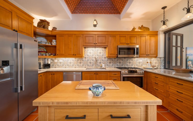 Full kitchen with wood cabinetry, patterned tile backsplash, and a butcher-block island