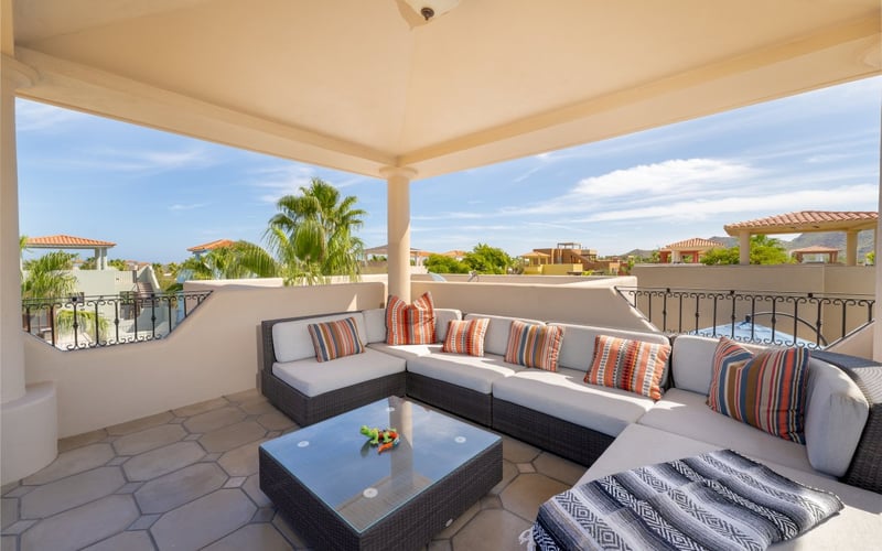 Covered rooftop terrace with sectional sofa and views over Loreto Bay rooftops and palm trees
