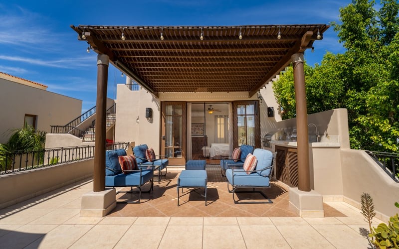 Covered pergola patio with blue lounge chairs and string lights at a Loreto Bay rental home